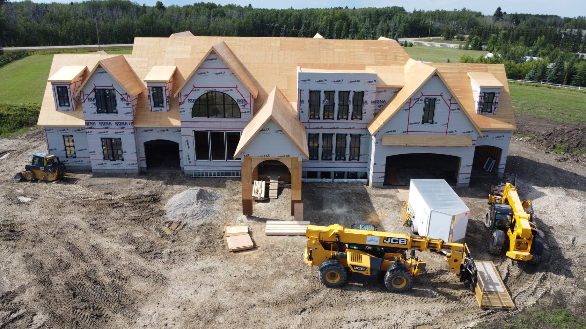 Aerial view of a large custom estate home at the framing stage near Calgary, Alberta